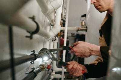 Technician inspecting commercial plumbing pipes in Cerritos